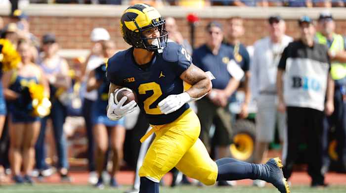Michigan RB Blake Corum runs with the ball while looking behind him